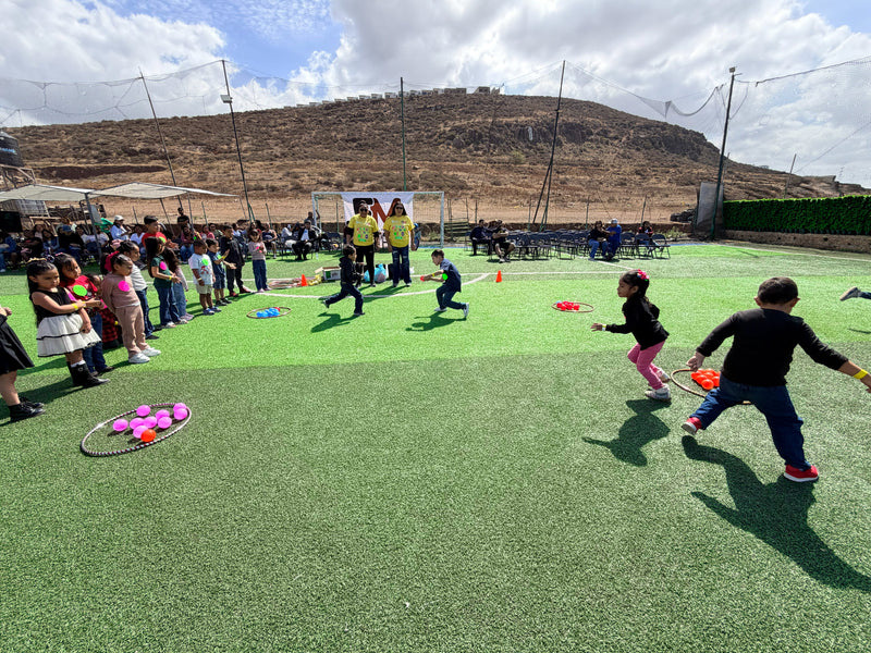Children playing outdoors on a grassy field with sports equipment at Rubber Mexico's Children Party