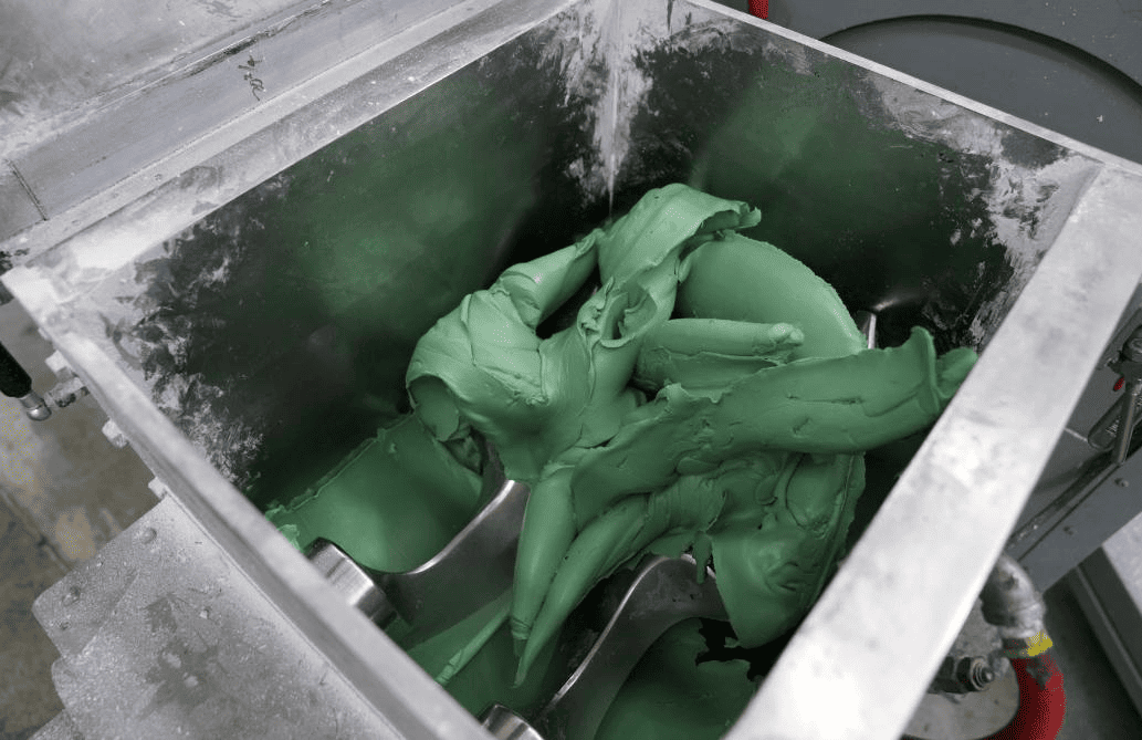 A steel compounding mixer with green rubber being mixed