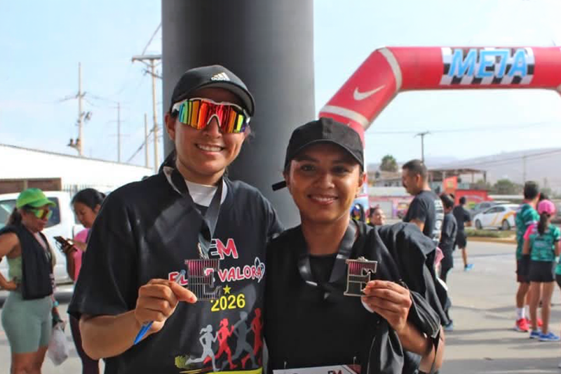 Two women standing each other holding a medal